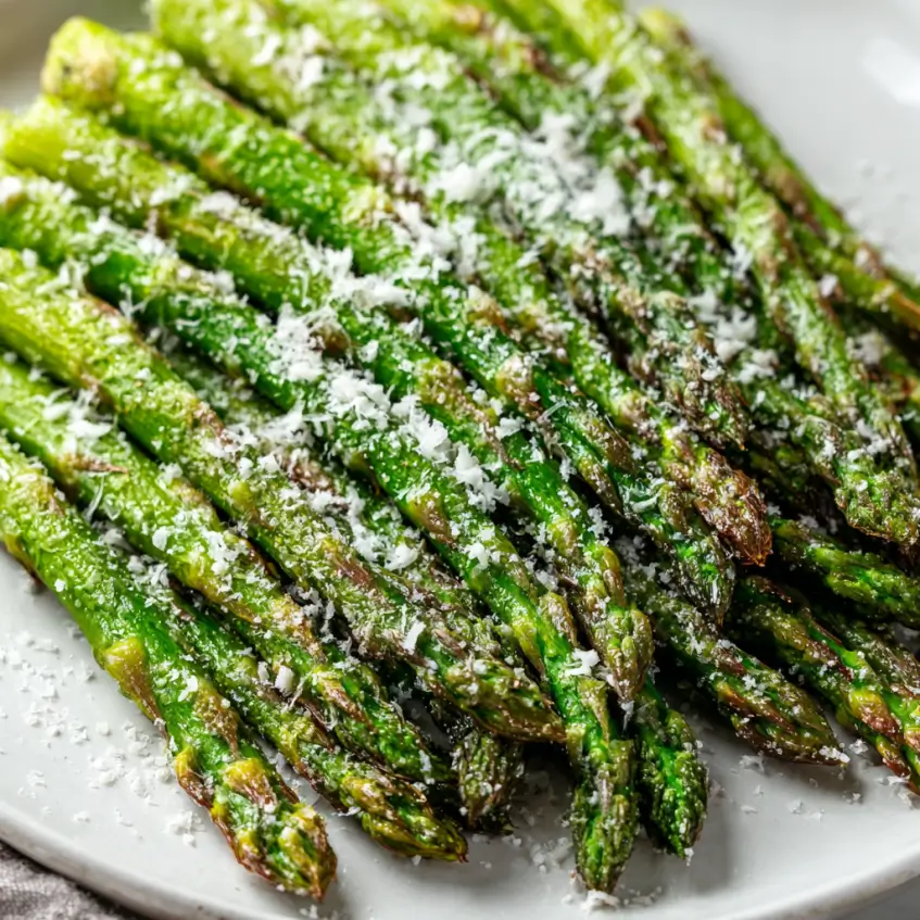 Deliciously crisp and tender air fryer asparagus spears, seasoned with Parmesan cheese and herbs, arranged on a plate and ready to enjoy as an easy side dish.