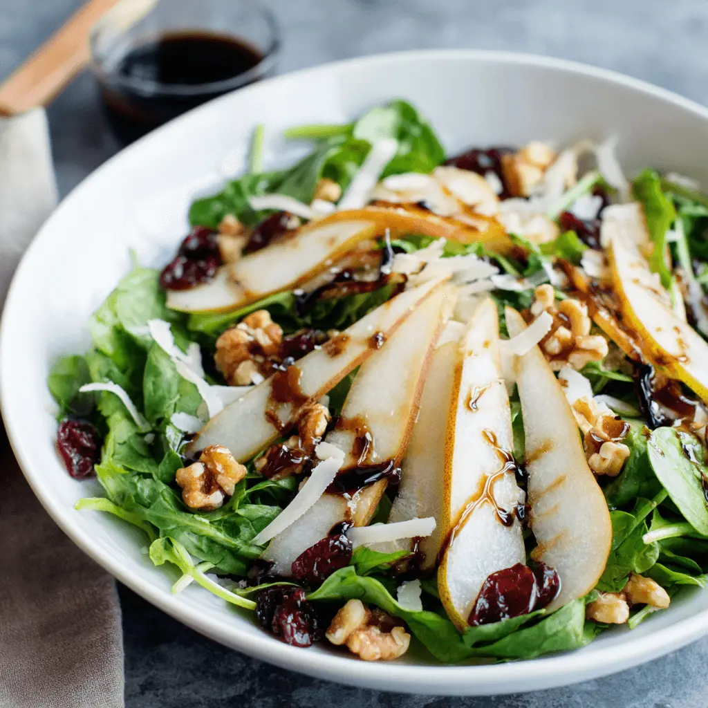 Vibrant close-up of a fresh pear and walnut salad with balsamic glaze, perfect for exploring pear salad recipes.