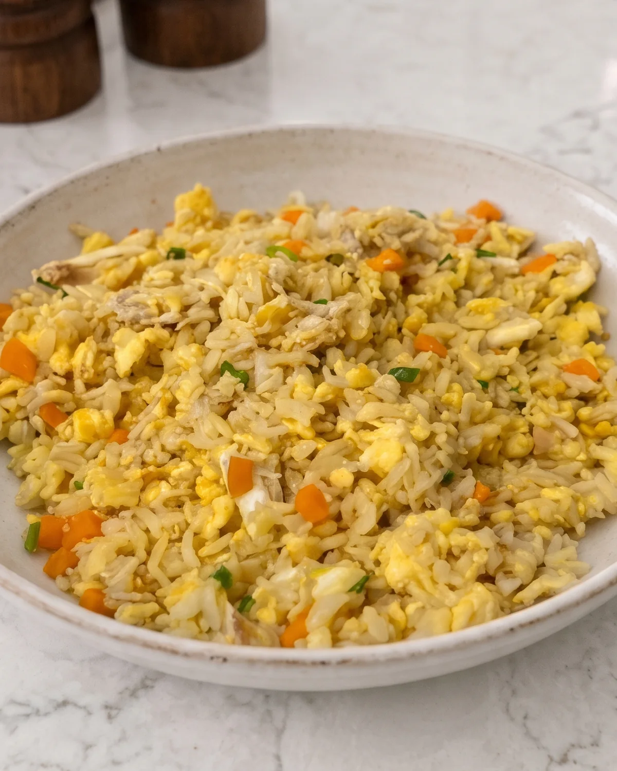 Easy Crab Egg Fried Rice 3 Bowl of crab egg fried rice with carrots, scallions, and golden egg on white marble